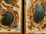 pair of gold framed mirrors with floral designs on them on a wall