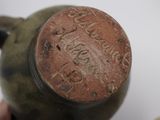 someone is holding a brown vase with writing on it in front of a bowl of fruit