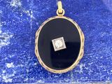 une image représentant un pendentif en forme de diamant noir et blanc posé sur une pierre bleue