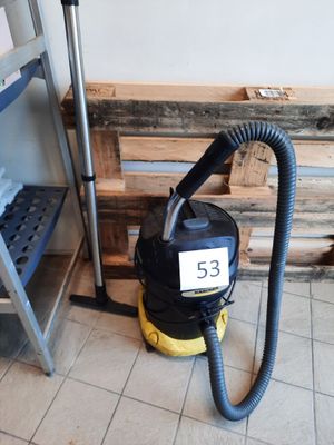 un aspirateur posé par terre à côté d'une étagère