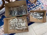 two boxes of silverware sitting on top of a blue and white rug
