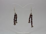 a pair of earrings with red beads hanging from them on a stand