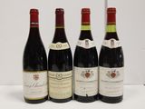 four bottles of wine are lined up on a table