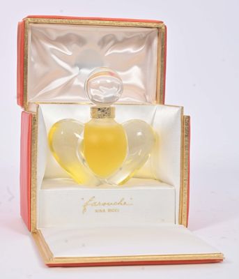 une boîte ouverte contenant un flacon de parfum, posée sur une surface blanche