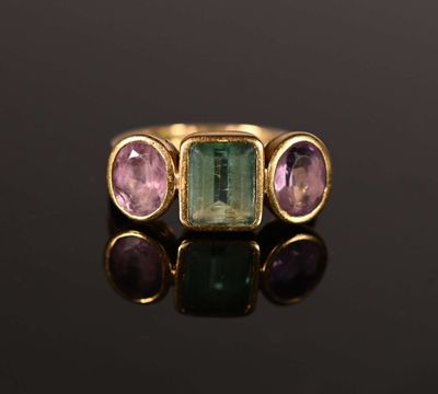 gros plan d'une bague en or avec trois pierres de couleurs différentes