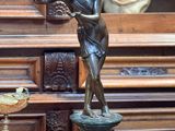 une statue représentant une femme tenant un oiseau à côté d'un vase