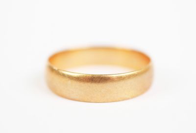 a close up of a gold wedding ring on a white surface