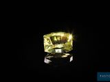 un diamant jaune dans l'obscurité, dont le reflet se dessine sur le sol
