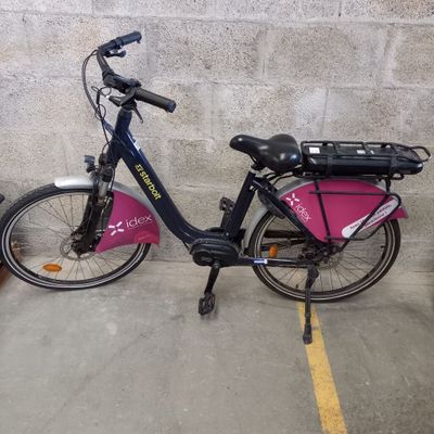 un vélo garé sur un parking, avec un sac à l'arrière