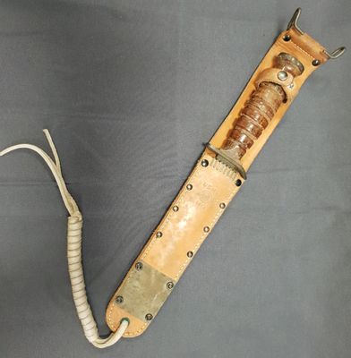 une photo d'un couteau à manche en bois posé sur une surface grise