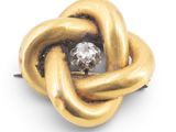 an image of a gold knot brooch with a diamond in the center