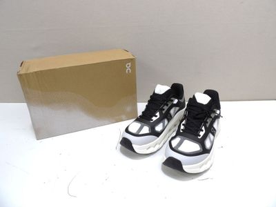 une paire de baskets noires et blanches posée sur une table, à côté d'une boîte