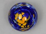 a blue and yellow glass ball on a white surface