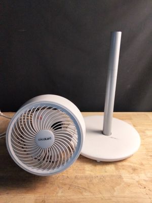 un petit ventilateur posé sur une table, à côté d'un téléphone