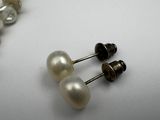 two pairs of pearl and silver earrings on a white surface