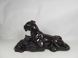 black ceramic figurine of a lion laying down on a white background