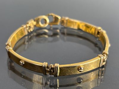 an image of a gold bracelet on a reflective surface
