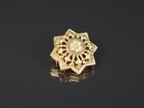 gros plan d'une broche en or sur une surface noire