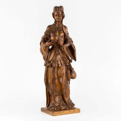 une statue en bois représentant une femme tenant un panier