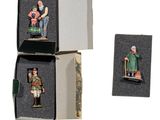 trois figurines miniatures représentant des personnages, dans une boîte