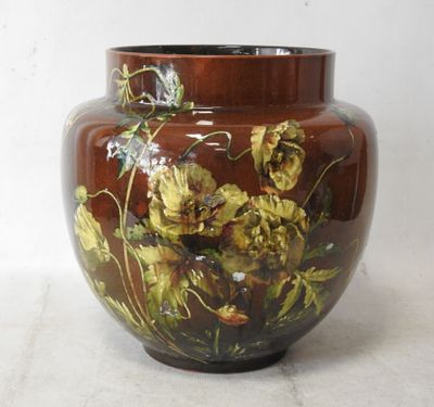 a brown vase with yellow flowers on it on a white surface