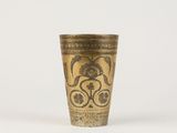 an old brass cup with a floral design on it