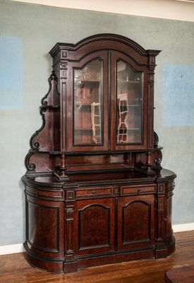 a wooden cabinet with a glass door in the corner of a room