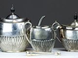 trois théières en argent posées sur une table blanche