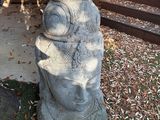 une statue en pierre représentant un visage, posée à même le sol