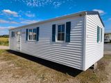 a white mobile home sitting on top of a dirt field
