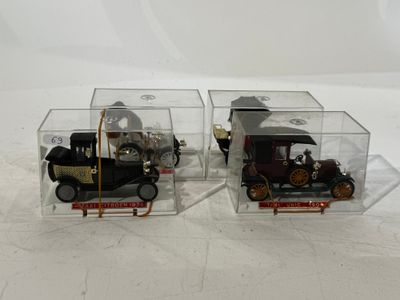 two small toy cars in a clear box on a white surface