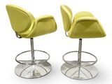 pair of yellow leather bar stools with chrome base and footrests