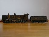 un petit train miniature posé sur une table en bois, avec un mur blanc en arrière-plan