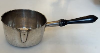 une casserole en argent avec une poignée noire posée sur une table blanche