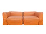 pair of orange leather sofas with ottomans on white background