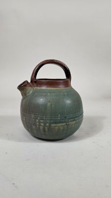 théière verte avec une poignée en bois sur fond blanc