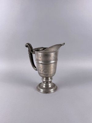 un pichet ancien en argent muni d'une anse, sur fond blanc
