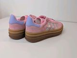 a close up of a pair of pink sneakers on a white surface