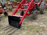 un tracteur rouge attelé à une charrue dans un champ