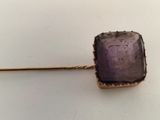 an image of a pin with a purple stone on it