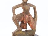 an image of a statue of a man sitting on top of a wooden block