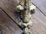 a gold candle holder on a wooden floor with a blue cord