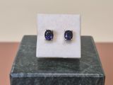 a pair of blue sapphire earrings sitting on top of a marble block