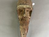 a close up of a wooden mask on a white surface