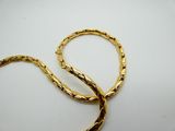 two gold bracelets on a white surface with a white background