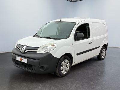 La camionnette blanche est garée dans une grande pièce au sol noir.