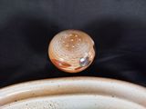a brown and white bowl with a lid on a black table