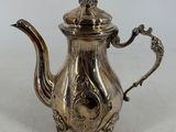 a silver tea pot with a bird on top of it