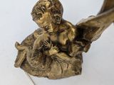 a statue of an angel holding a baby on a leaf