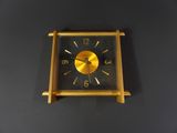 a gold clock on a black wall with a black background